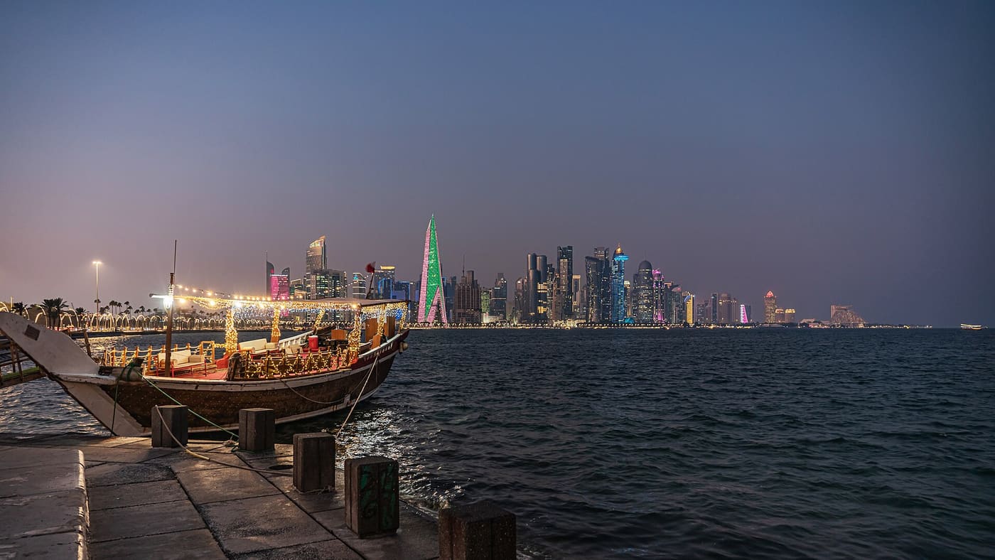 Traditional dhow moored on the Doha Corniche with the illuminated West Bay skyline behind